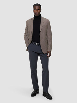 Ein Mann, der statt des klassischen Schwarz einen schwarzen Rollkragenpullover aus Merinowolle, eine GEN2-Hose und schwarze Lederschuhe trägt.