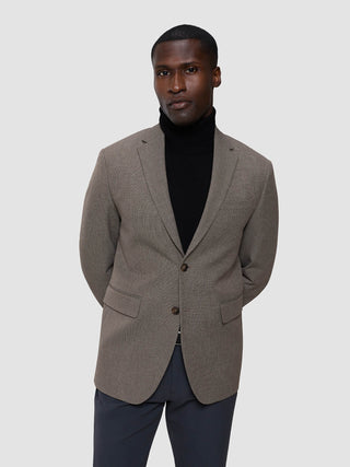 Ein Mann, der einen schwarzen Rollkragenpullover der Marke „Cooler than classic“ unter einem „Essential“-Blazer trägt.