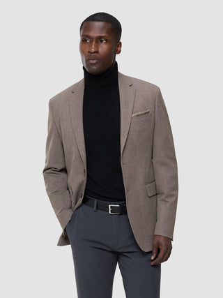 Ein Mann, der einen „Cooler than classic“-Blazer in Schwarz über einem schwarzen Rollkragenpullover und einer GEN2-Hose trägt.