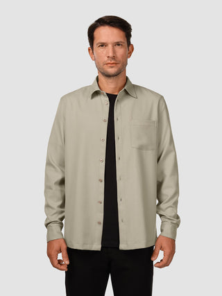 Ein Mann, der ein „Effortless Shirt“ in der Farbe „Stone Beige“ über einem schwarzen T-Shirt trägt.