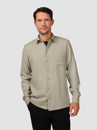 Ein Mann, der ein „Effortless Shirt Stone Beige“-Hemd mit Knopfleiste und Brusttasche über einem schwarzen T-Shirt trägt.