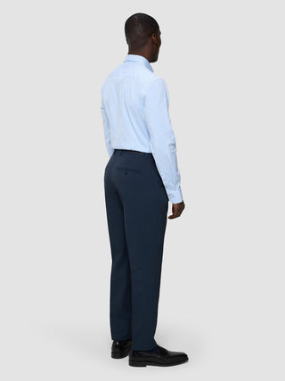 Ein Mann, von hinten gesehen, der ein hellblau gestreiftes, dünnes „Elevated“-Hemd in regulärer Passform, eine dunkle Hose und schwarze Slipper trägt.