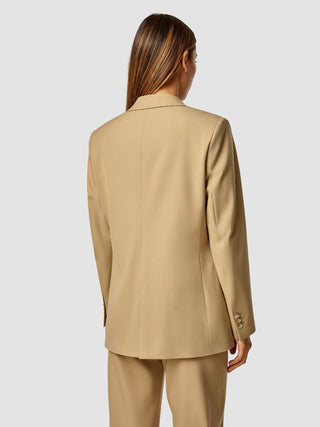 Eine Frau, von hinten gesehen, die einen „Essential Blazer Caramel“ trägt.