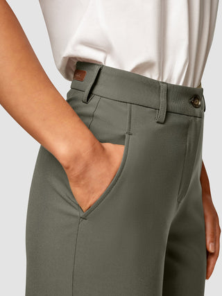 Eine Seitenansicht einer Person, die eine „Essential Pants Straight Dark Olive“ trägt und eine Hand in der Tasche hat.