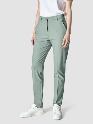 Eine Person, die eine „Essential Pants Tapered“ in der Farbe „Calm Green Melange“, ein weißes T-Shirt und weiße Sneaker trägt und damit ein klares, skandinavisches Design verkörpert.
