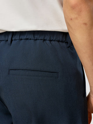 Nahaufnahme der Rückseite der marineblauen „Essential Pants Relaxed Fit Navy Melange“ mit elastischem Bund und einer einzelnen Paspeltasche.