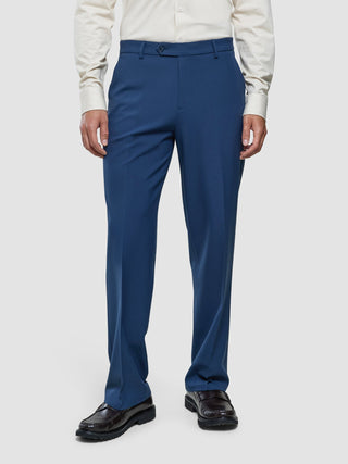 Eine Person, die ein helles Hemd mit Knöpfen, eine Essential-Anzughose in Relaxed Fit in Marineblau und dunkle Slipper trägt.