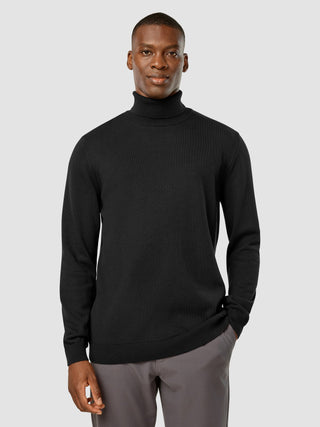 Ein Mann, der den „Everyday Knit“ Rollkragenpullover in Schwarz trägt.