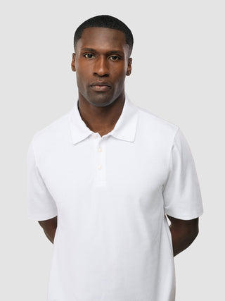 Ein Mann, der das „Evolve Pique Polo White“ trägt – ein schlichtes Must-have für den Sommer.