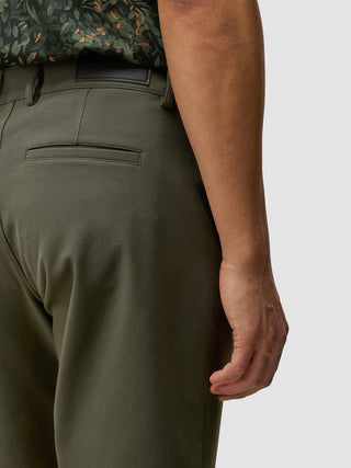 Eine Person, die GEN2™-Shorts in der Farbe „Muted Green“ und ein gemustertes Hemd trägt.