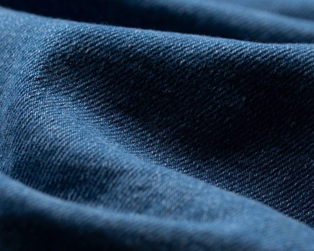 Nahaufnahme eines blauen Denim-Stoffes mit sichtbarer Köperstruktur.