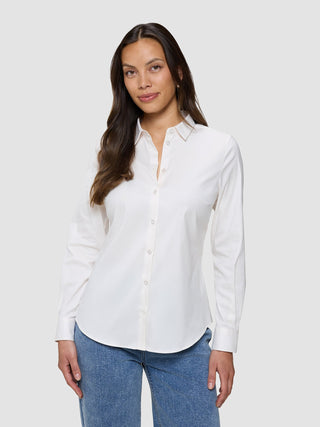 Eine Frau, die ein weißes Damen-Oxford-Hemd White Orchid Slim mit klassischem Kragen und eine blaue Jeans trägt.