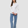 Eine Frau, die ein Damen-Oxford-Hemd White Orchid Slim mit klassischem Kragen trägt, das in eine blaue Jeans gesteckt ist, dazu schwarze Loafer.