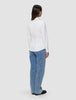 Eine Person, von hinten gesehen, die ein Damen-Oxford-Hemd White Orchid Slim und eine blaue Jeans trägt.