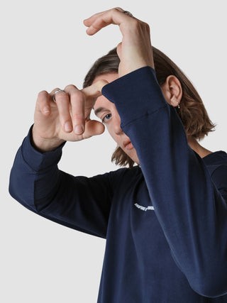 Eine Person, die ein langärmeliges „Supima Autograph“-T-Shirt in Marineblau trägt, formt mit ihren Händen vor ihrem Gesicht ein Herz.