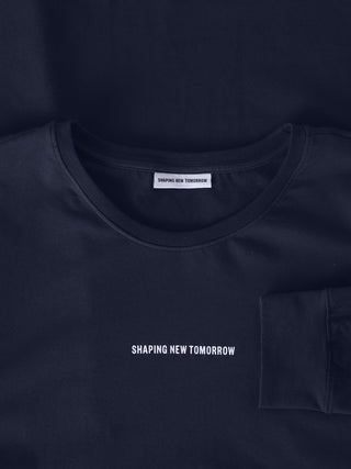 Ein marineblaues Supima Autograph Langarm-T-Shirt mit dem Markennamen „SHAPING NEW TOMORROW“, der auf der Brust aufgedruckt ist und sich auch auf dem Innenetikett am Hals wiederfindet, das ein klares, skandinavisches Design verkörpert.