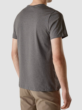 Eine Person, von hinten gesehen, die ein Supima Autograph T-Shirt in Dunkelgrau und eine hellbraune Hose mit 360°-Stretch trägt.