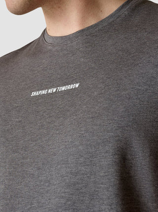 Ein dunkelgraues Supima Autograph T-Shirt mit dem Aufdruck „SHAPING NEW TOMORROW“ auf der Brust, das sich durch ein klares, skandinavisches Design auszeichnet.