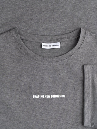 Ein dunkelgraues Supima Autograph T-Shirt mit dem Markennamen „SHAPING NEW TOMORROW“, der auf der Brust und auf dem Etikett im Nacken aufgedruckt ist.