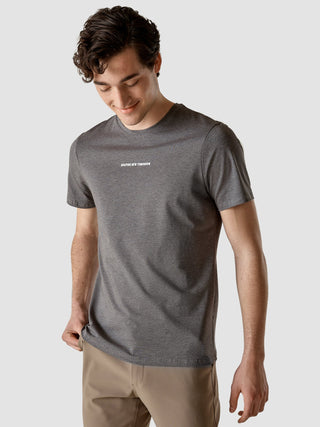 Ein Mann, der ein dunkelgraues „Supima Autograph“-T-Shirt trägt, auf dessen Brust in skandinavischem Design der Schriftzug „SHAPING NEW TOMORROW“ aufgedruckt ist.