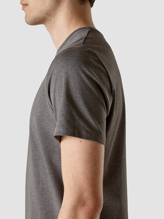 Eine Seitenansicht einer Person, die ein Supima Autograph T-Shirt in Dunkelgrau mit 360°-Stretch trägt.