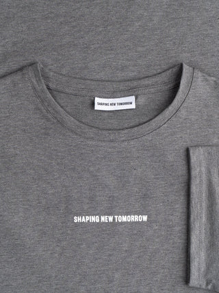 Ein dunkelgraues Supima Autograph T-Shirt mit dem Markennamen „Shaping New Tomorrow“ auf der Brust und auf dem Innenetikett am Halsausschnitt, das sich durch minimalistisches skandinavisches Design auszeichnet.