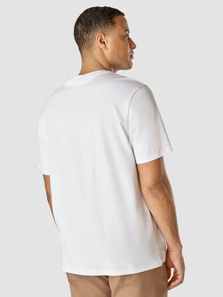 Ein Mann, von hinten gesehen, der ein Supima-T-Shirt „Box Fit Legacy“ in Weiß und Beige sowie eine Hose mit 360°-Stretch trägt.