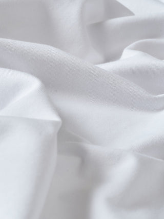 Nahaufnahme eines Supima-T-Shirts „Box Fit Legacy White“ mit weichen, klaren Stofffalten.