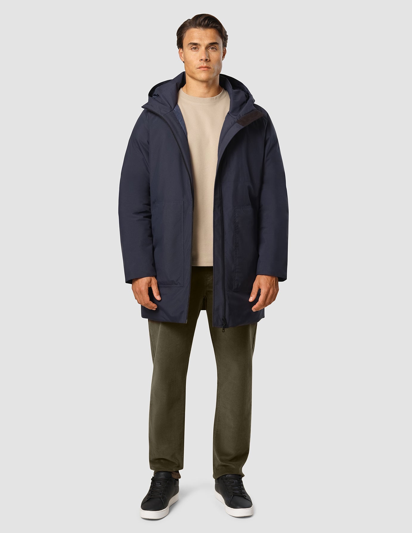 Ein Mann, der eine Utility-Jacke in Dunkelblau über einem beigen Pullover und einer olivgrünen Hose trägt.