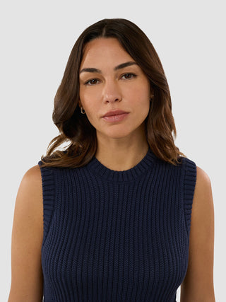 Eine Frau, die das „Women’s Structured Knit Top Navy“ trägt, blickt in die Kamera.