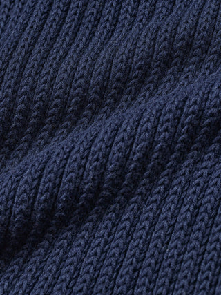 Eine Nahaufnahme von gefaltetem, marineblauem, geripptem Strickstoff aus einem strukturierten Damen-Strickoberteil in Marineblau.