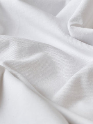 Nahaufnahme der Falten im weißen Supima-T-Shirt-Stoff.