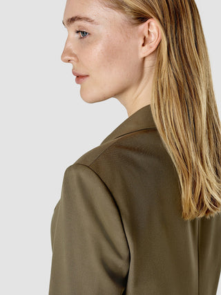 Profilansicht einer Frau, die einen „Essential Suit Straight“ Blazer in Dunkeloliv trägt.