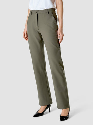 Eine Person, die eine Hose „Essential Suit Straight Dark Olive“, ein weißes T-Shirt und schwarze Pumps mit spitzer Zehenpartie trägt.