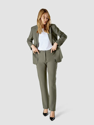 Eine Frau, die einen „Essential Suit Straight“ in der Farbe „Dark Olive“ über einem weißen T-Shirt trägt.