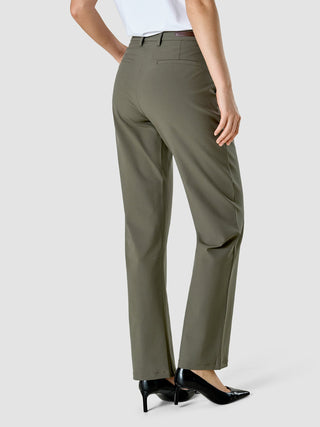 Eine Person, von hinten gesehen, die eine Hose „Essential Suit Straight Dark Olive“ und schwarze Pumps mit spitzer Zehenpartie trägt.