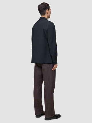 Eine Person, von hinten gesehen, die ein Atelier Overshirt Dark Navy, eine Atelier-Hose und schwarze Schuhe trägt.