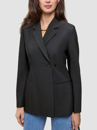 Eine Frau, die einen schwarzen Women’s Avira Blazer Black mit spitz zulaufendem Revers und eine blaue Jeans trägt, die das skandinavische Design zur Geltung bringen.