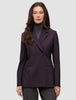 Ein Model trägt den Damenblazer Avira in der Farbe Burgundy Berry – einen dunkelburgunderroten Zweireiher im minimalistischen skandinavischen Design – über einem grauen Rollkragenpullover.
