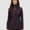 Ein Model trägt den Damenblazer Avira in der Farbe Burgundy Berry – einen dunkelburgunderroten Zweireiher im minimalistischen skandinavischen Design – über einem grauen Rollkragenpullover.