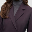 Eine Person trägt einen Avira-Blazer für Damen in der Farbe Burgundy Berry über einem grauen Rollkragenpullover und präsentiert damit eine klare, skandinavische Designästhetik.