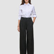 Eine Person, die ein weißes Hemd trägt, das in eine schwarze Damenhose Avira Pants Wide Black gesteckt ist.