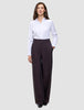 Eine Person, die ein weißes, langärmeliges Hemd mit Knöpfen trägt, das in die Damenhose Avira Pants Wide in der Farbe Burgundy Berry gesteckt ist.