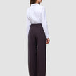 Eine Frau, von hinten gesehen, die ein weißes Hemd trägt, das in die Damenhose Avira Pants Wide in der Farbe Burgundy Berry gesteckt ist.