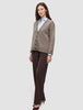 Eine Frau, die eine Damen-Strickjacke aus weicher, grobstrickiger Wolle in Taupe-Melange über einem hellblauen Hemd mit Kragen und einer dunklen Hose trägt.