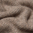 Nahaufnahme einer Damen-Strickjacke aus weicher, grobstrickiger Wolle in Taupe-Melange, die sich durch eine dicke, taupefarbene Grobstrick-Struktur aus Merinowolle auszeichnet.