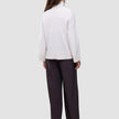 Eine Person, von hinten gesehen, die einen Damen-Rollkragenpullover aus weicher, grobstrickiger Wolle in der Farbe Sugar Melange sowie eine dunkle Hose mit weitem Bein trägt.