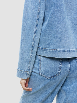 Eine Person, die eine klassische Damen-Jeansjacke in der Farbe „Snow Blue Wash“ und dazu passende Stretch-Jeans trägt.
