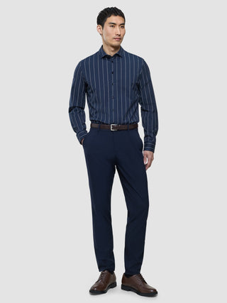 Ein Mann, der ein „Classic Shirt Midnight Pinstripes Regular“, eine dunkle Hose mit einem braunen Gürtel und braune Leder-Anzugschuhe trägt.