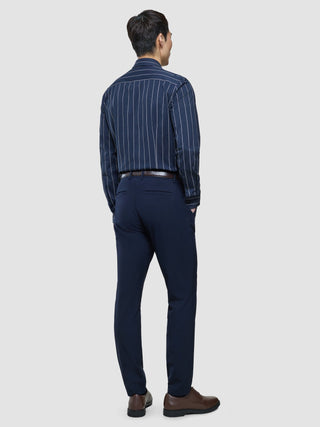 Ein Mann, von hinten gesehen, der ein „Classic Shirt Midnight Pinstripes Regular“ trägt, das in eine marineblaue Hose gesteckt ist, sowie braune Anzugschuhe.